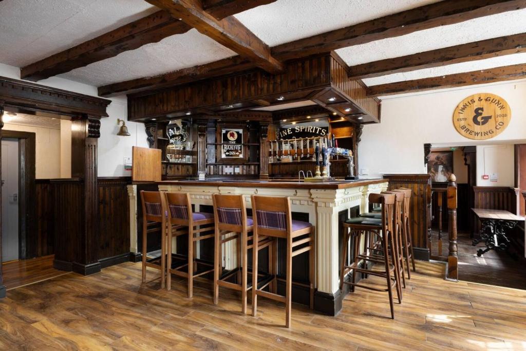 a bar with wooden bar stools in a room at The Tavern in Buchlyvie