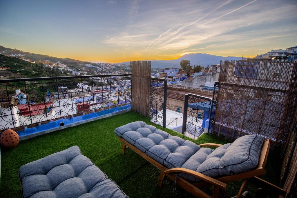 a balcony with couches and a view of a city at Alojamientos Chaouni in Chefchaouen