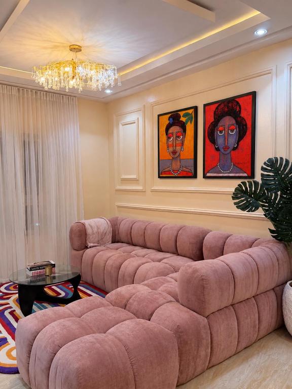a large pink couch in a living room with paintings at Maison Madame - Female only Shared Apartment Lekki in Lekki