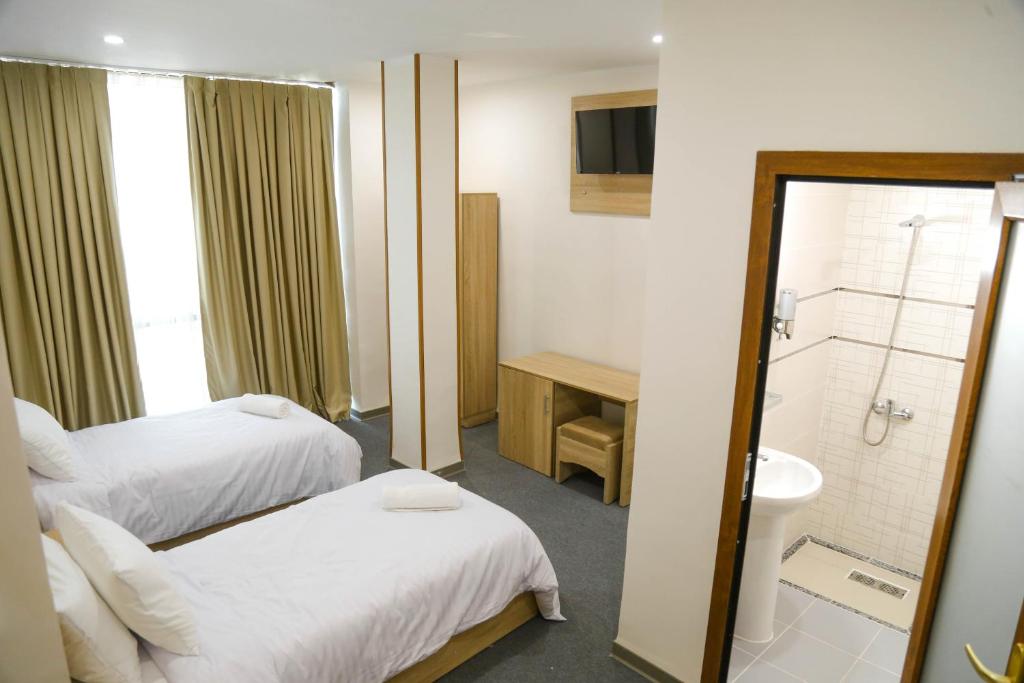 ein Hotelzimmer mit zwei Betten und einem Badezimmer in der Unterkunft Cristam in Biskra