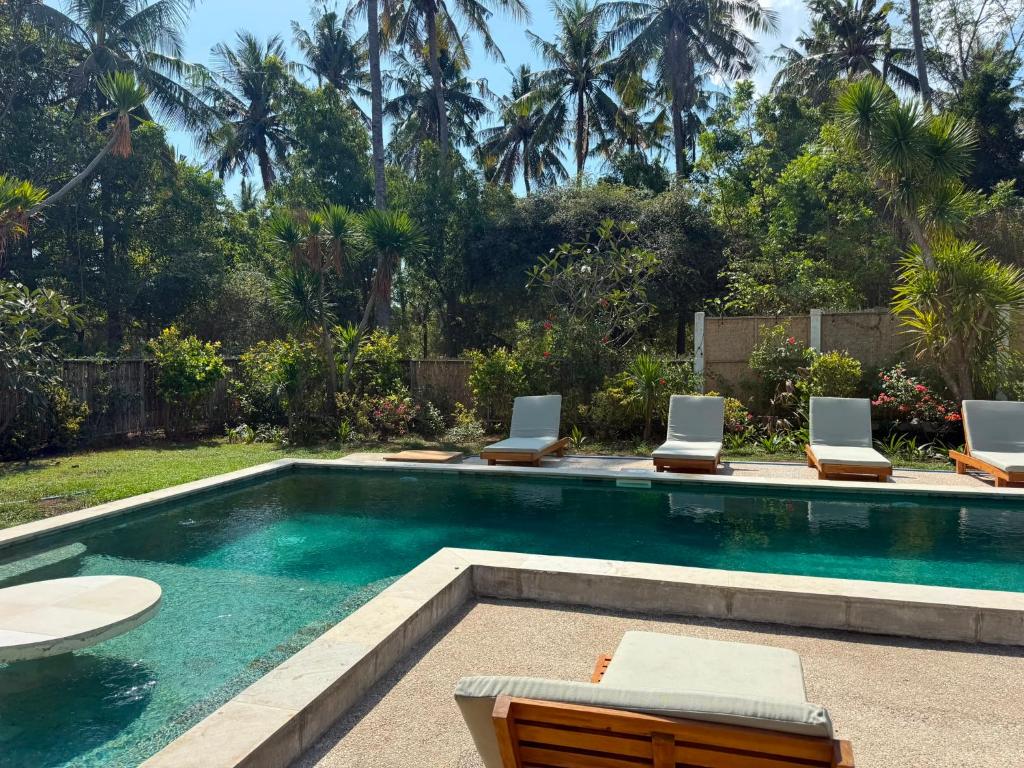 a swimming pool with lounge chairs and a swimming pool at 3 Bedroom Private House - Tir Na Nog in Gili Trawangan