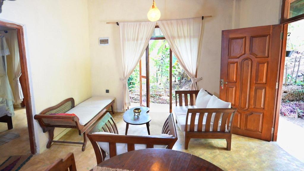 a living room with a couch and chairs and a table at Kethbima Agri Cottage in Amunugama