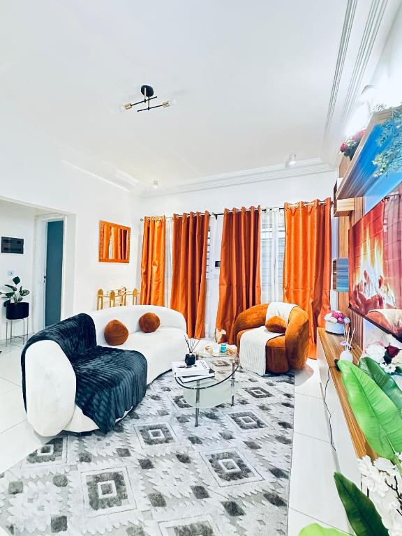 a living room with orange curtains and a couch at Dyden luxury appartement in Douala