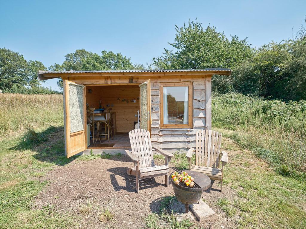 a small cabin with two chairs and a table at The Hoppers Hut in Weald