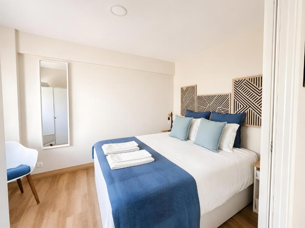 a bedroom with a blue and white bed and a chair at Lovely & Comfy 3 in Estoril