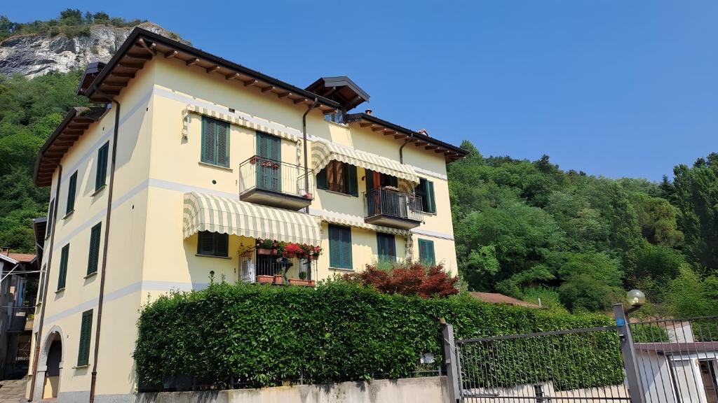 a yellow building with windows and a fence at Maison Adriano Lago Maggiore in Sangiano