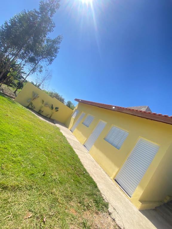 a yellow house with a grassy hill next to it at Pousada San Matheus in São Miguel Arcanjo