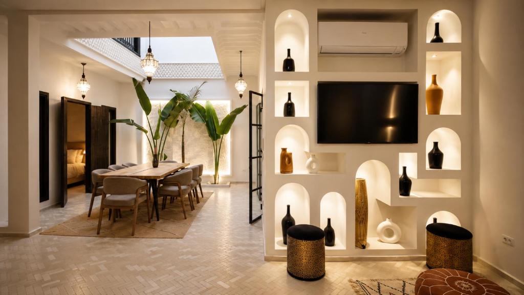 a dining room with a table and a tv on the wall at Riad privé Maskat, piscine, petit-déjeuners, proche Jemaa el-Fna in Marrakesh