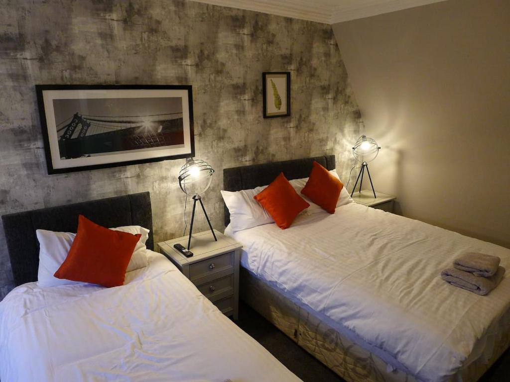 two beds in a room with two lamps on tables at Saltoun House in Fraserburgh