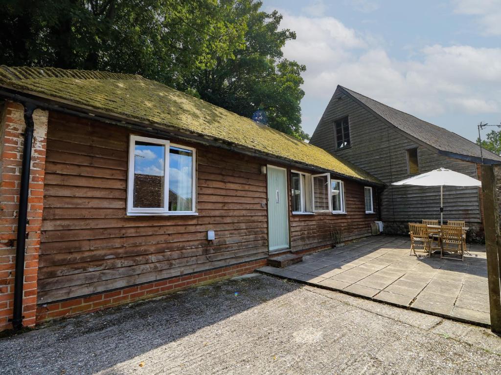 a small house with a patio and an umbrella at Byre Cottage 2 in Pulborough