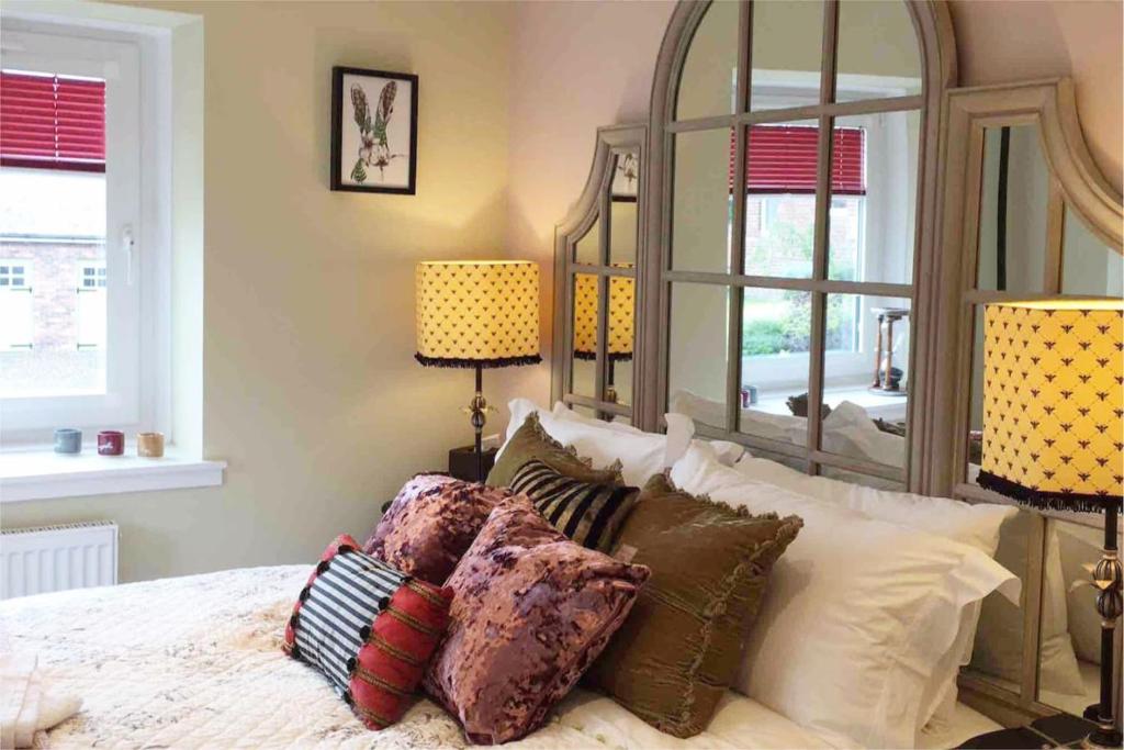 a bedroom with a bed with pillows and a large mirror at The Little Beech Tree in Linlithgow