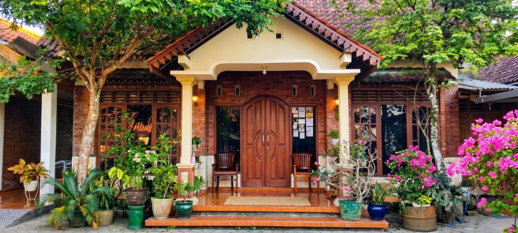 a house with a wooden door and a bunch of potted plants at Homestay Syariah Melati Borobudur in Borobudur