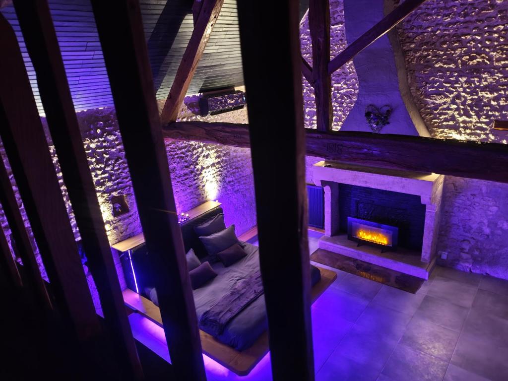 a room with a fireplace with purple lighting at L'Expérience in Villermain