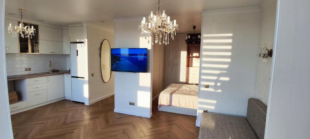 a room with a kitchen with a bed and a chandelier at Gorgeous view apt riscanovca in Chişinău