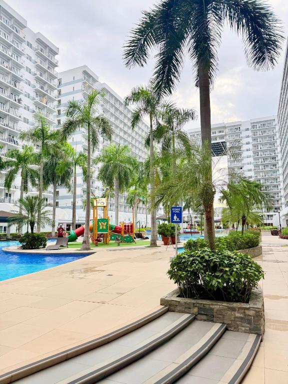 a resort pool with palm trees and a playground at Shell Residences Manila by PauL in Manila