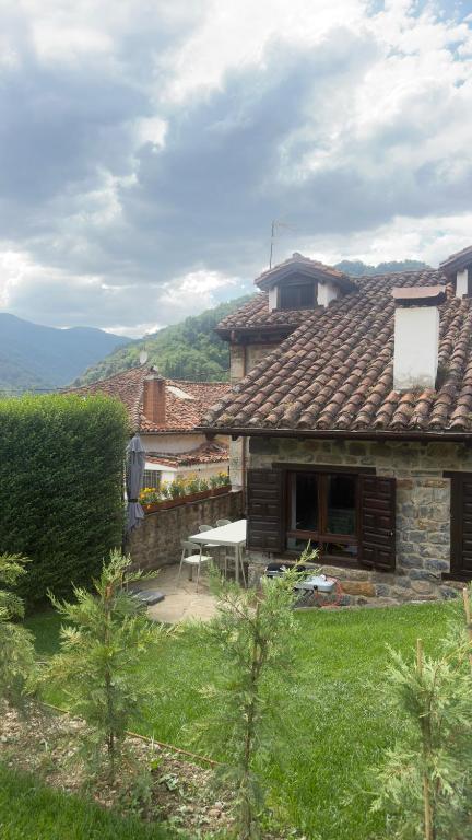 a stone house with a picnic table in a yard at Explora Picos de Europa in Cosgaya