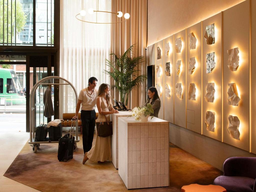 a group of people standing at a counter in a lobby at Mercure Melbourne La Trobe Street in Melbourne