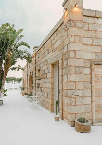 a brick building with a palm tree in front of it at Treviè Suite - Torre San Giovanni in Fontanelle