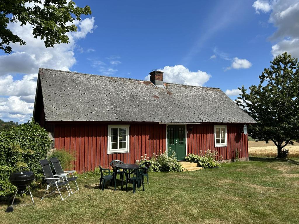 ein rotes Haus mit einem Tisch und Stühlen davor in der Unterkunft Olles in Vessigebro