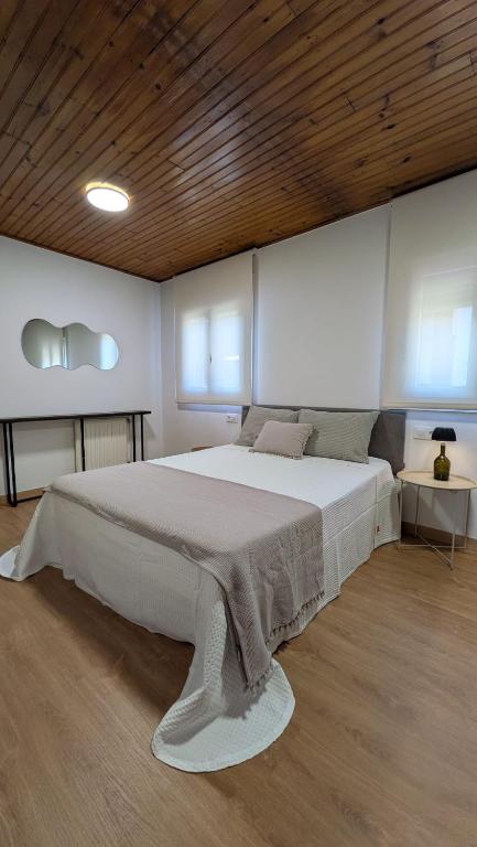 a bedroom with a large white bed with a wooden ceiling at Casa da Cerca in Cenlle