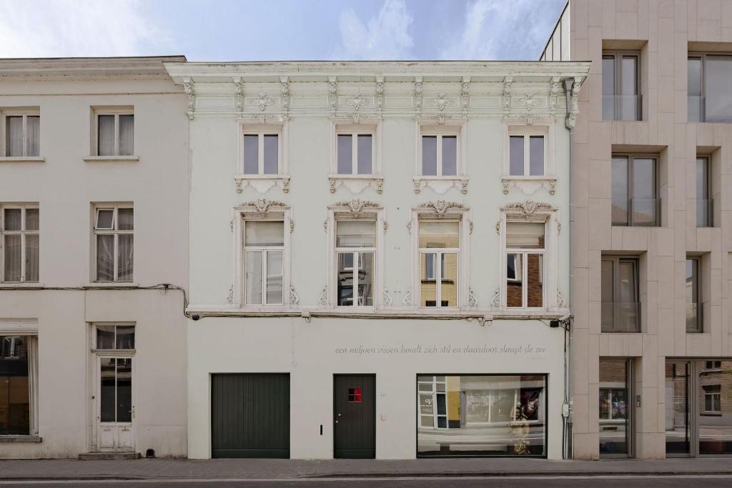 a white building with a red door on a street at Boutique Hotel Verne Dreams in Ghent