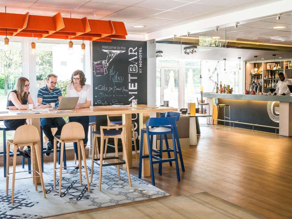 a group of people sitting at a table in a restaurant at Novotel Saclay in Saclay
