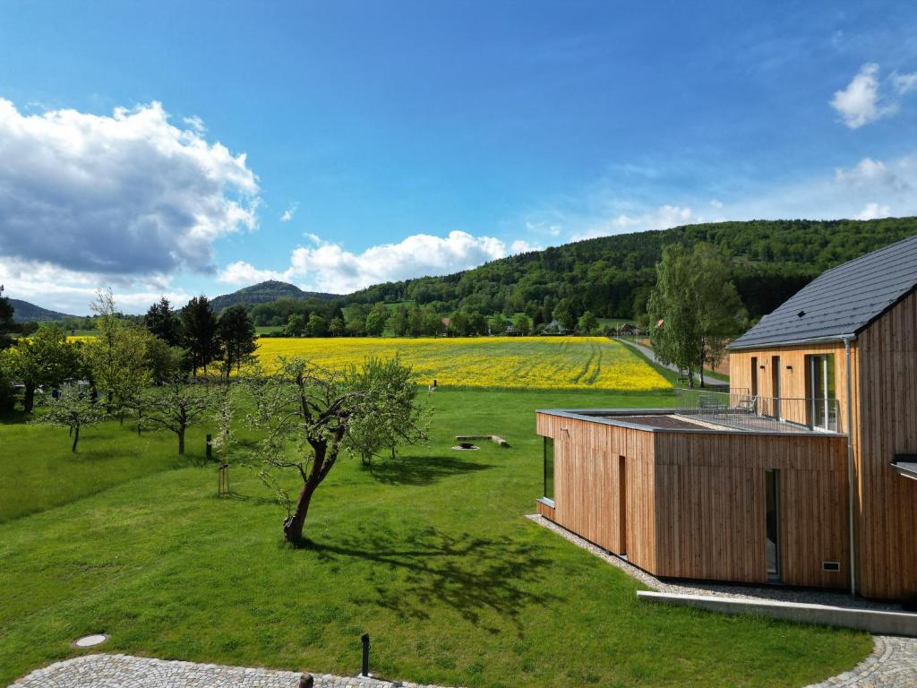 a small wooden building in a field with a house at Ferienhaus Weitsicht in Großschönau