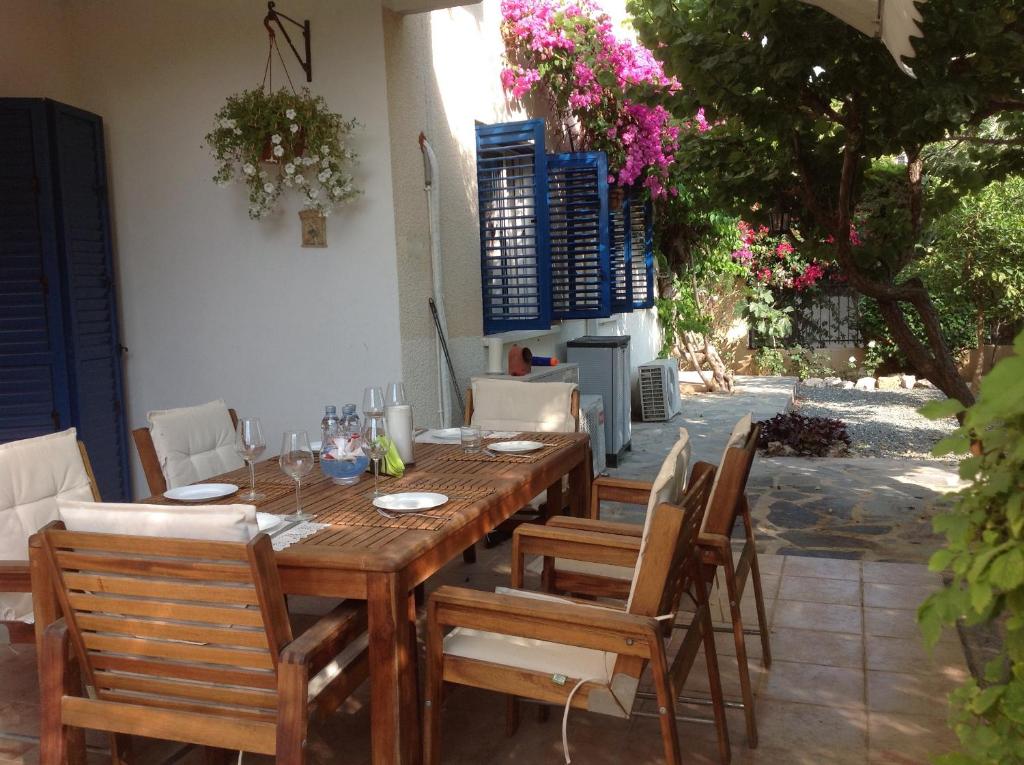 uma mesa de madeira e cadeiras num pátio com flores em Kings Apartment with private Garden em Pafos