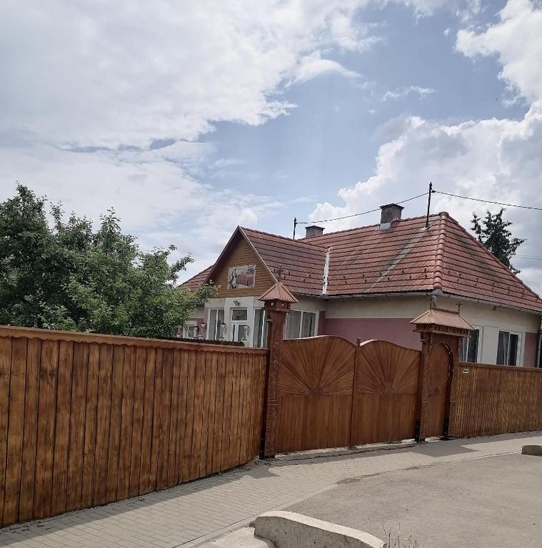 a house with a wooden fence and a wooden gate at Sófalvi Vendégház in Sîntimbru