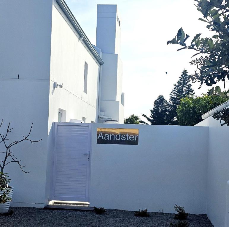 a white building with a gate with a sign on it at Aandster in Paternoster
