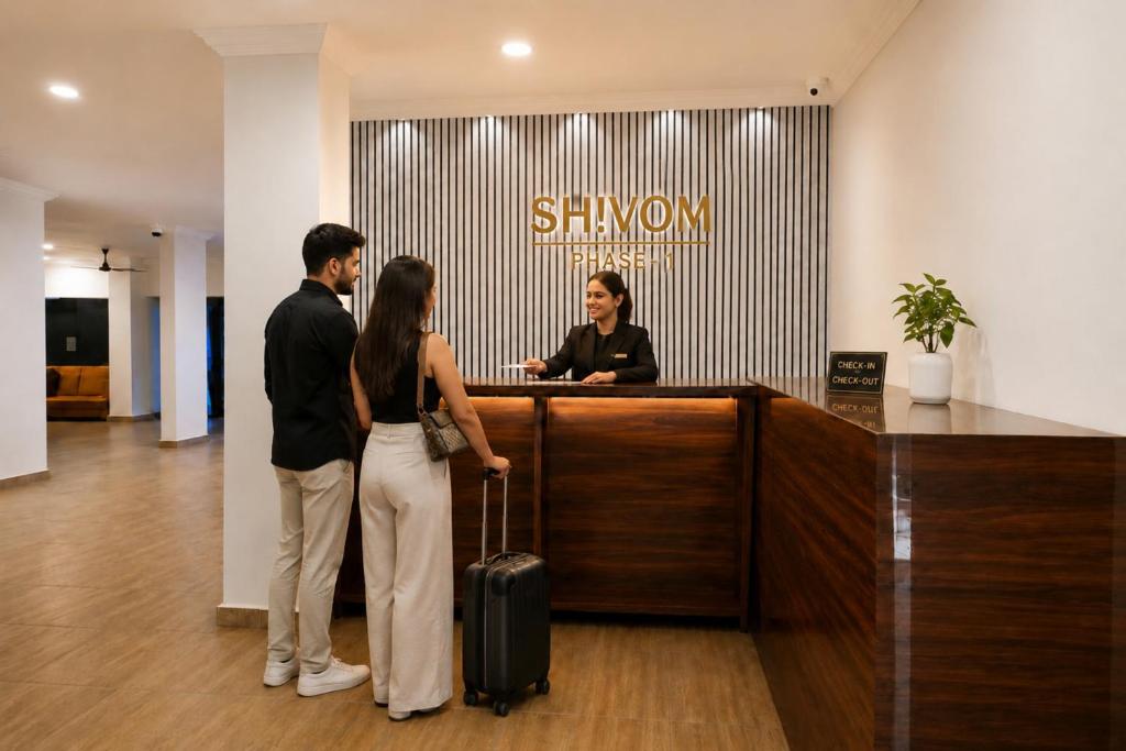 a man and a woman standing at a desk with a woman with a suitcase at Resort SH!VOM Phase-1 in Calangute