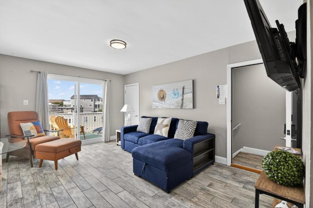 a living room with a blue couch and a tv at Radiant Beach Block Condo Parking Patio in Brigantine