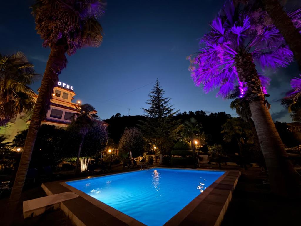 a swimming pool at night with palm trees at Hotel Palma in Gjirokastër