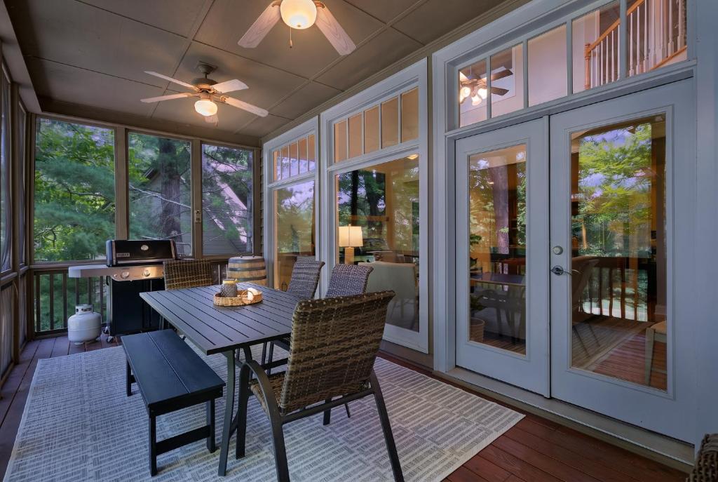 a screened in porch with a table and chairs at K-Tees Cottage - Big Canoe,GA - Soak in the Private Hot Tub, Challenge Friends in the Arcade, Take in Scenic Golf Course Views, in Holcomb
