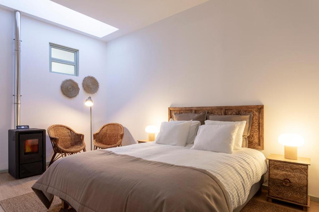 a bedroom with a large bed and two chairs at Casa em bairro típico de Aveiro in Aveiro