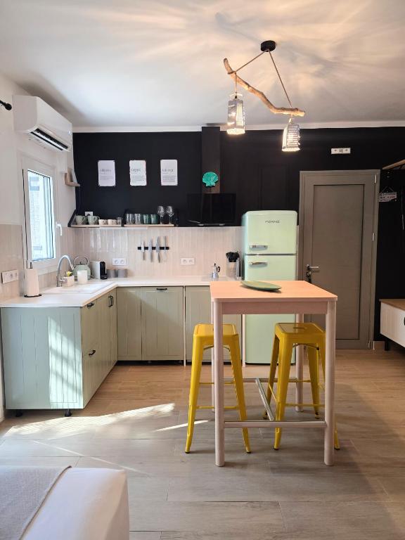 a kitchen with a table and two yellow stools at Kalamea Apartment Kalathas in Kalathas