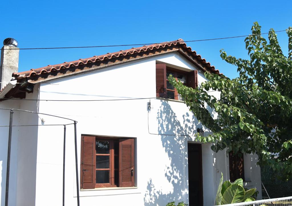 a white house with brown windows and a tree at Nonna Sofia in Krikellos
