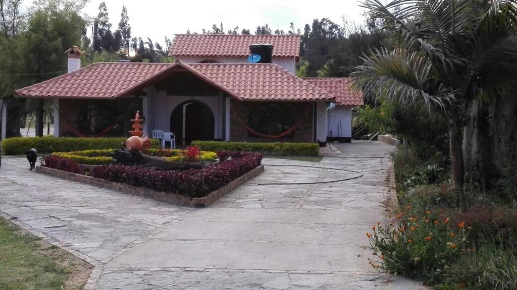 a house with a flower garden in front of it at Finca Villa Patricia in Paipa