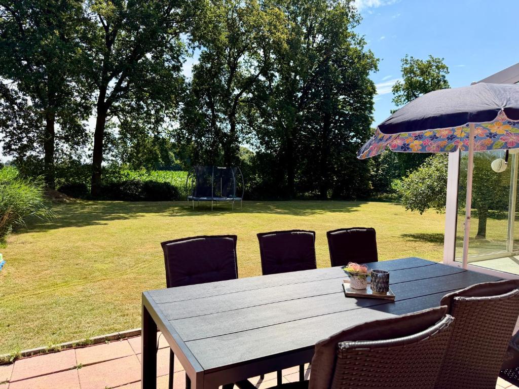 a wooden table with chairs and an umbrella at Fehntjer Ferienhof nahe Idasee in Ostrhauderfehn