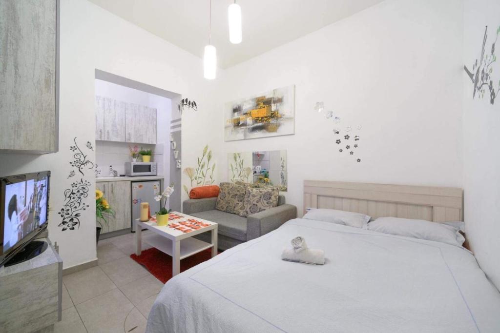 a white bedroom with a bed and a living room at דירת סטודיו ליד הים ברחוב בוגרשוב המבוקש in Tel Aviv
