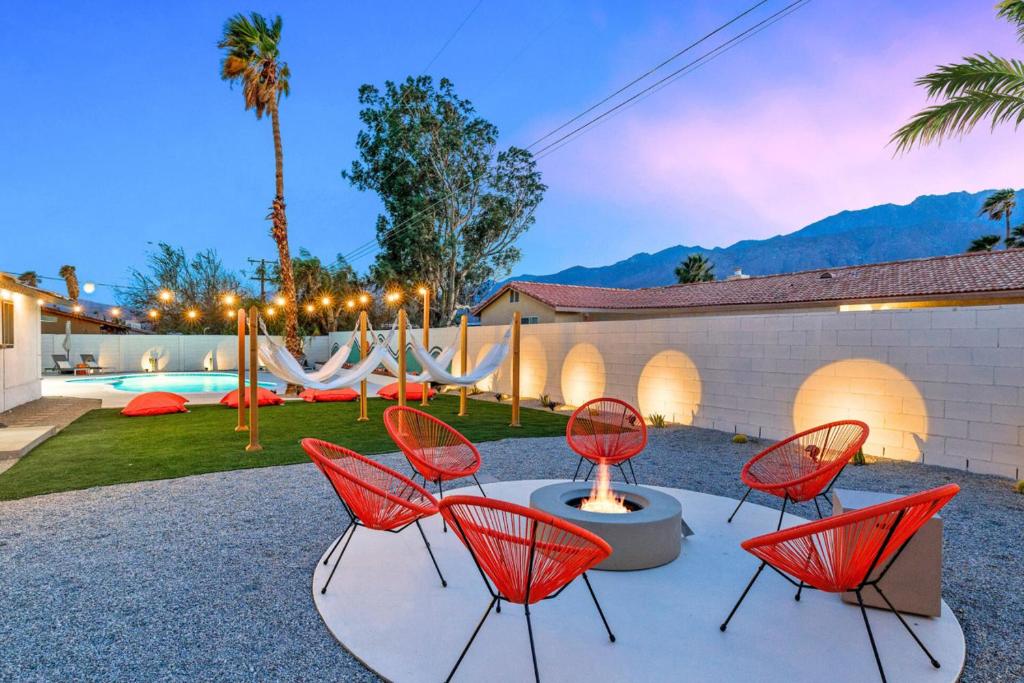 a group of red chairs sitting on a patio at Acacia Retreat by Rather Be Properties in Palm Springs