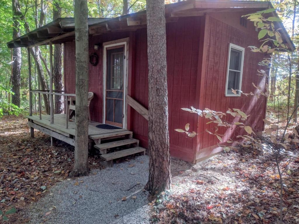a red house with a porch in the woods at Thunder Ridge Cabins B&B - Bird Nest in Rockbridge