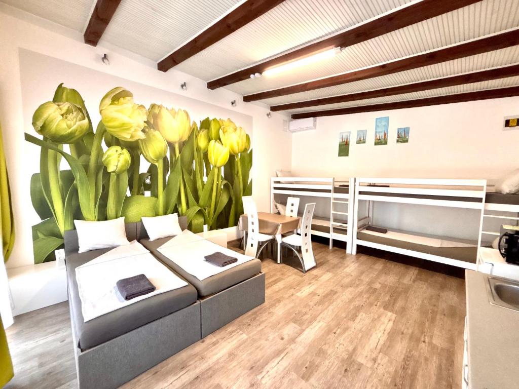 a room with two beds and a painting of flowers on the wall at Tutti Apartman in Balatonlelle