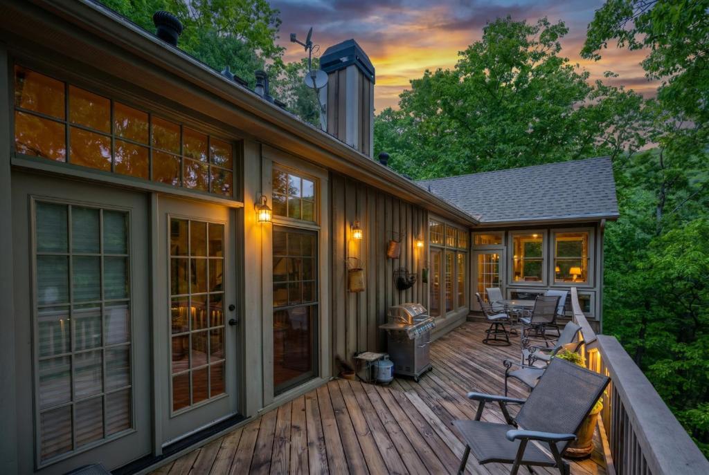 a deck with chairs and tables on a house at - Dawsonville, GA - Take in Beautiful Lake Views, Kick Off a Game of Foosball, Cozy Up by the Fireplace, and Unwind on the Scree in Dawsonville