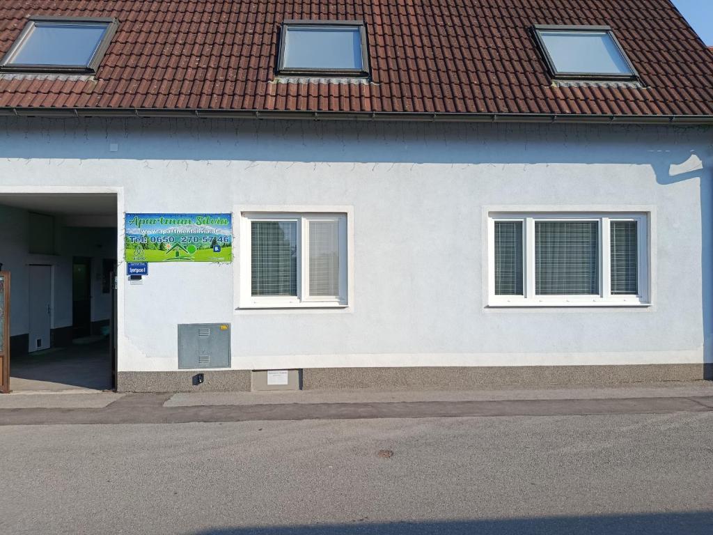 a white building with two windows and a door at Apartman Silvia in Breitenau
