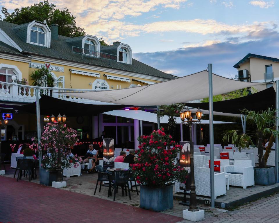 a restaurant with a white canopy and tables and flowers at Y Panzió in Balatonlelle
