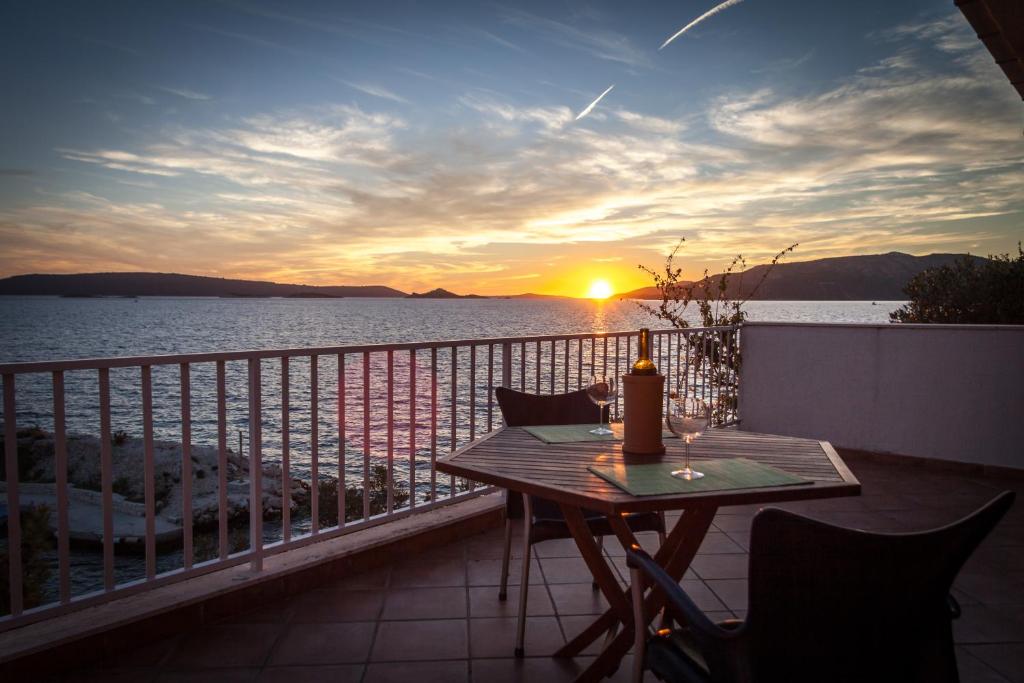 a table and chairs on a balcony with a sunset at Apartments Sundance in Okrug Donji