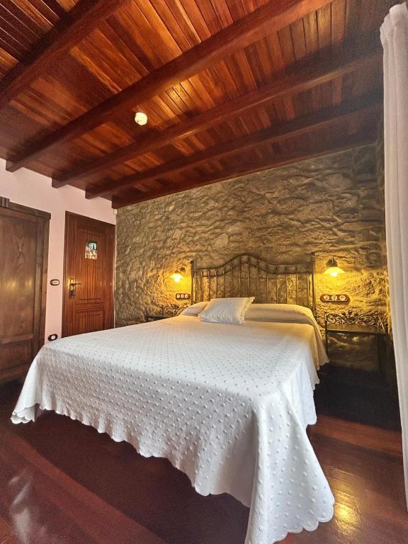 a bedroom with a bed with a stone wall at Casa de Costoia in Santiago de Compostela