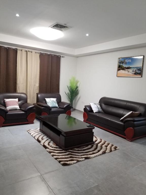 a living room with black couches and a coffee table at Eden Heights in Tokuse