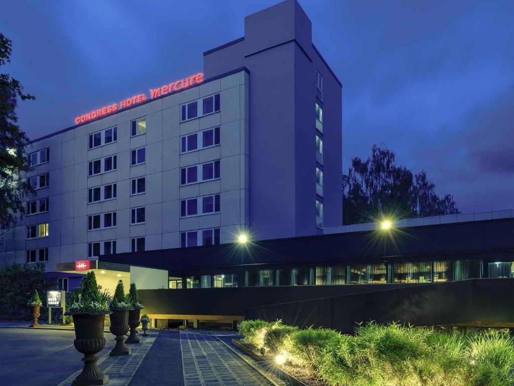 a white building with a red sign on it at Congress Hotel Mercure Nürnberg an der Messe in Nuremberg